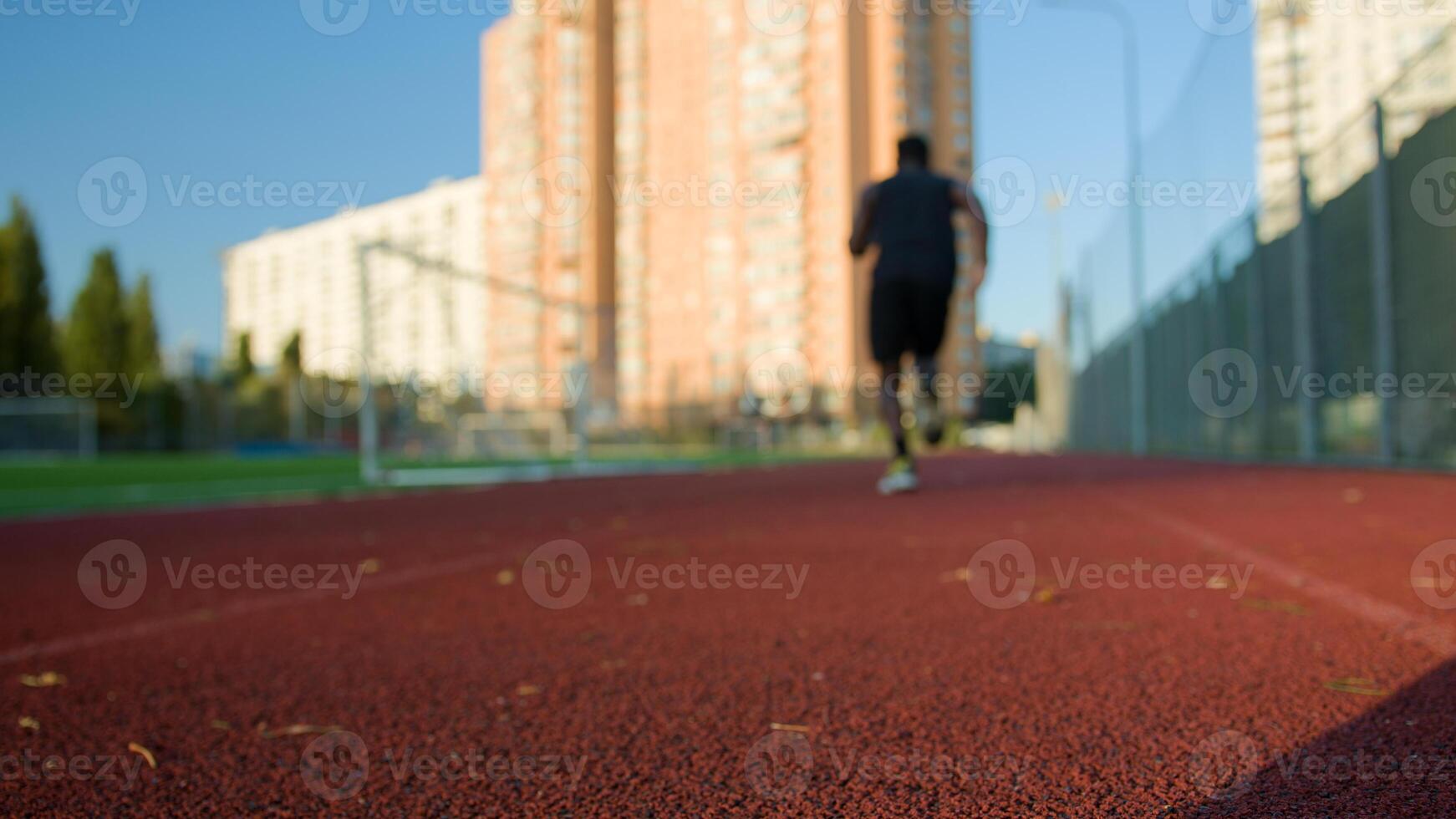 Back view runner in low start position on stadium running track male sportsman jogger ready start run marathon jogging outdoors African American unknown sport man morning jog healthy active lifestyle photo