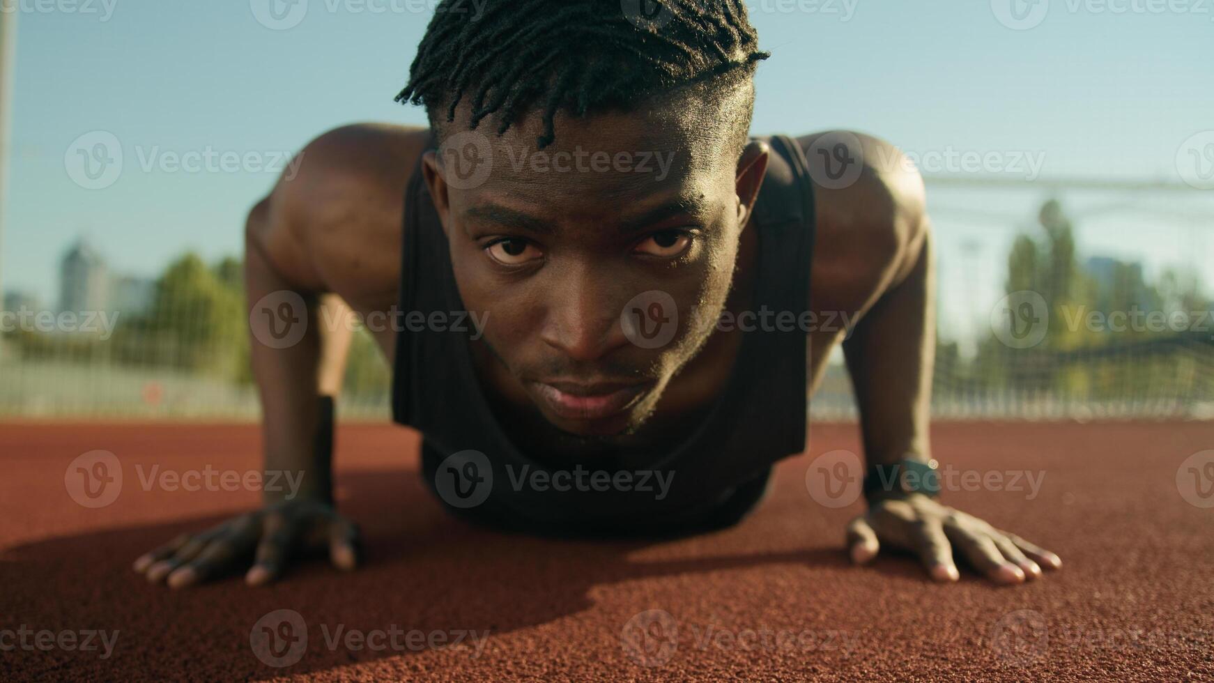 Athletic bodybuilder African American sportsman young man doing push-up exercise on football stadium male strong athlete fitness training muscles strength workout outdoors sport health and motivation photo
