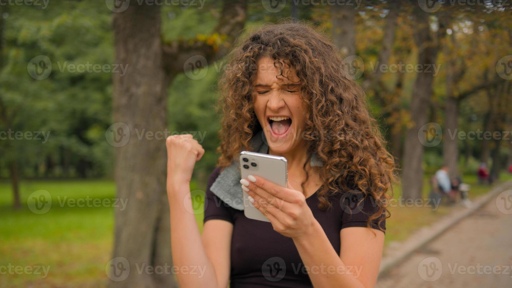 Happy Caucasian young gen z woman amazed shocked fitness girl with mobile phone smartphone shout yes winning prize online sport bet champion female sportswoman win celebrate victory in city outdoors photo