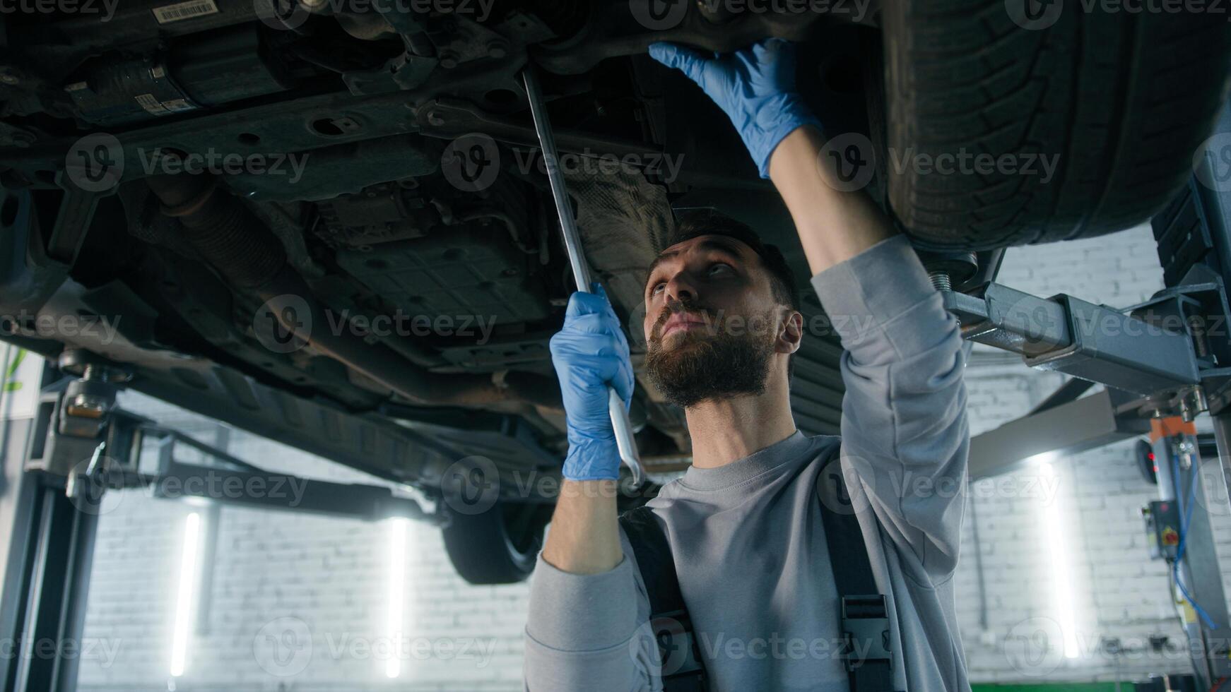 Caucasian man guy technician repairman auto mechanic repair truck in car service station male working underneath lifting vehicle in garage transport maintenance fixing automobile with mechanical tool photo