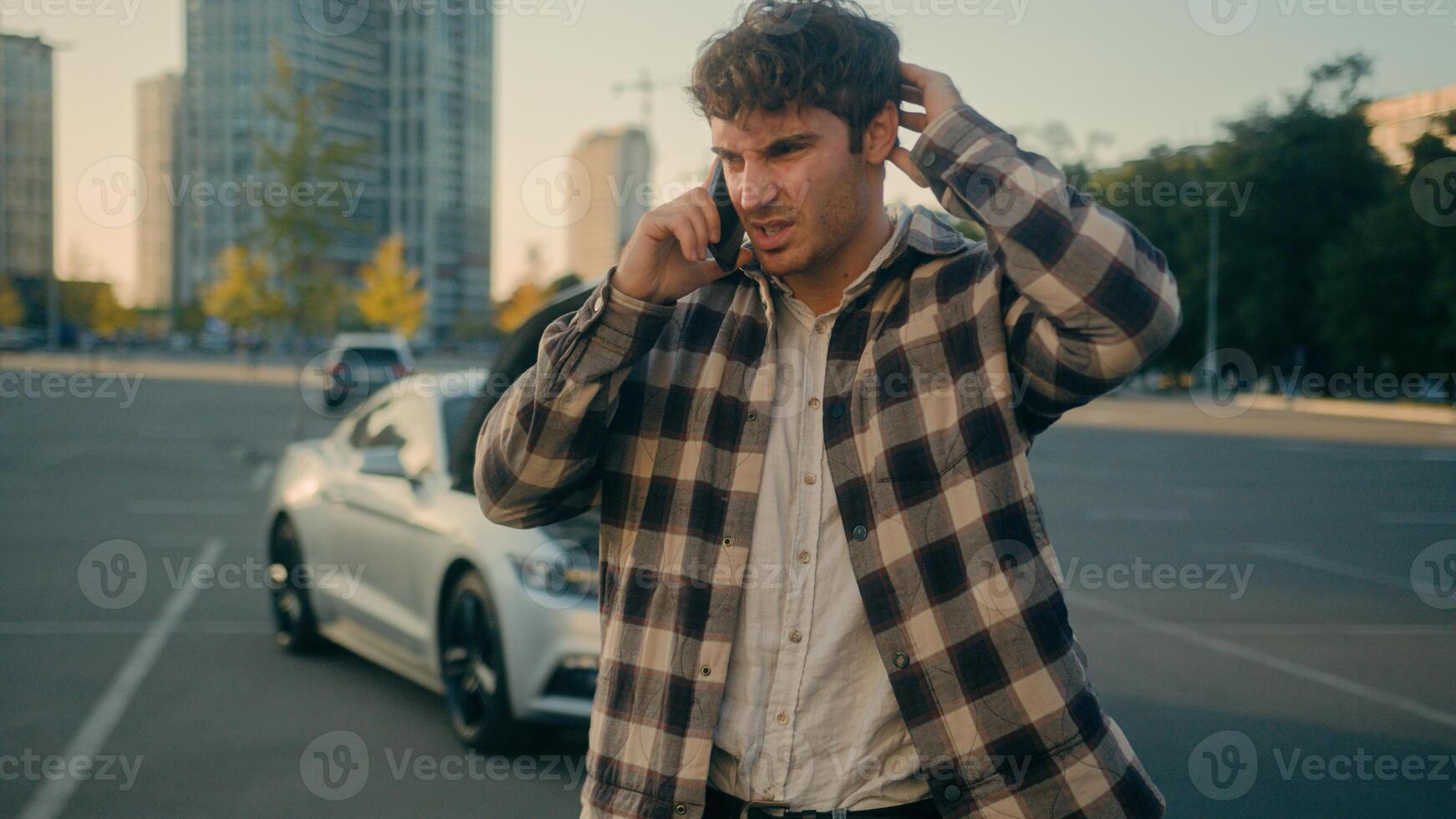 Worried stressed man driver Caucasian guy talk mobile phone calling car service engine problem stand on road outdoors broken car background vehicle breakdown damaged automobile wreck need help in city photo