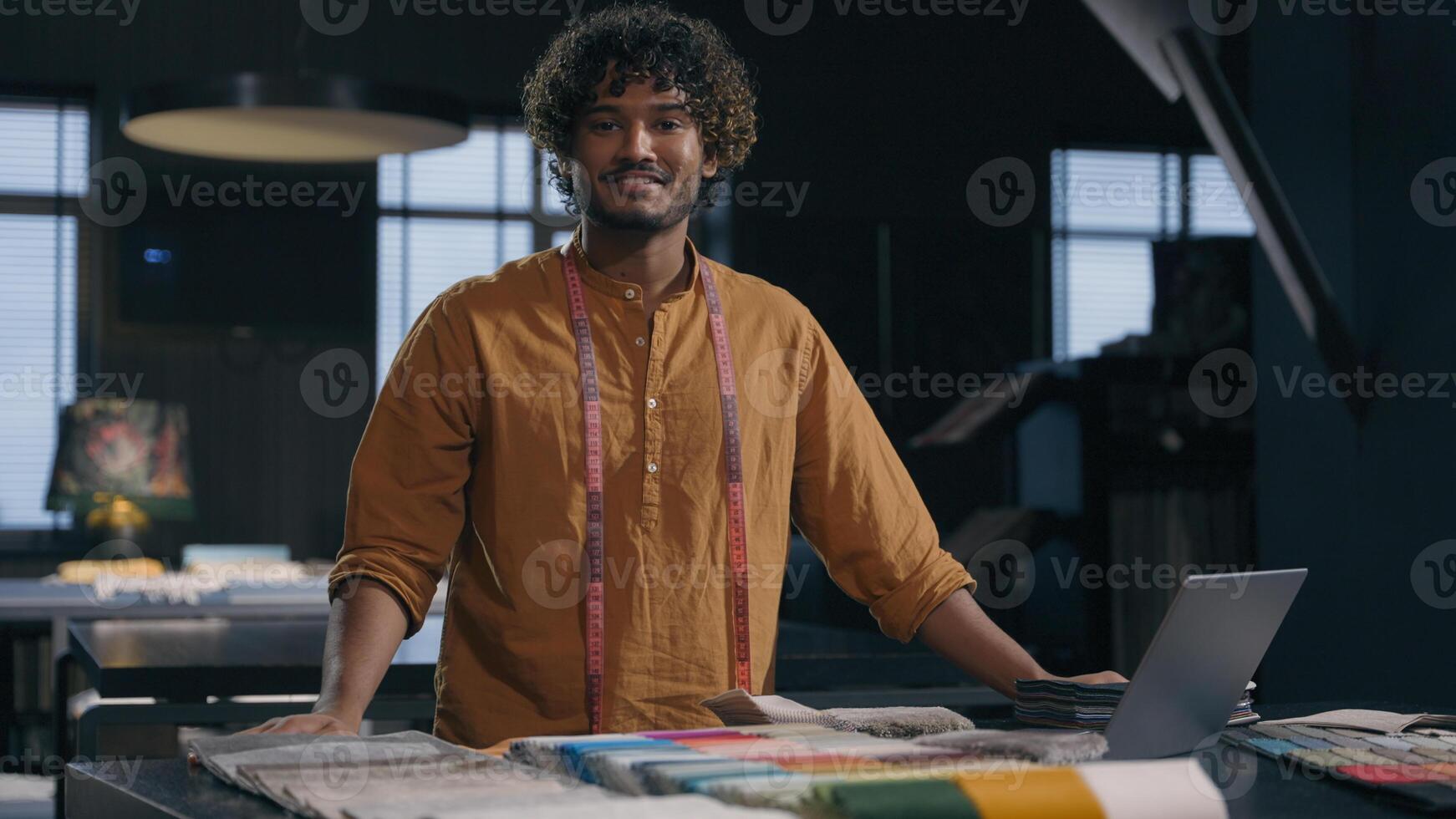 Portrait of happy Indian Arabian man cloth designer at modern tailoring dressmaking studio smiling male tailor couturier in garment workshop small business hand craft fashion fabric clothing design photo
