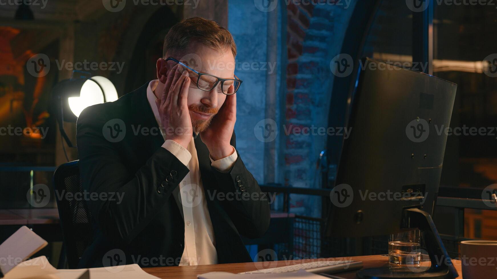 Caucasian businessman guy business man male worker working computer at night overtime office late time deadline feel headache pain head ache migraine tired exhausted fatigued overworked health problem photo