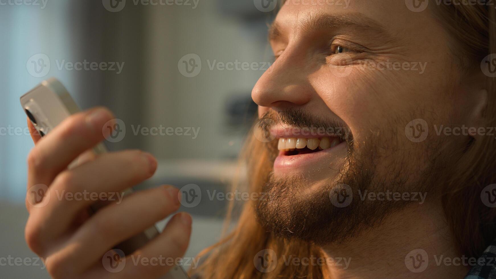 Caucasian man male user customer guy homeowner boyfriend happy smiling talking loudspeaker smartphone cellphone device gadget ai translator mobile phone call record audio message voice mail at home photo
