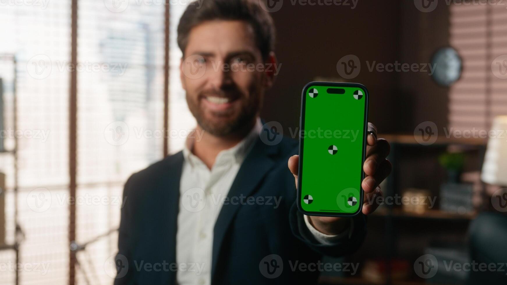 Smiling Caucasian middle-aged business man adult businessman guy male employer entrepreneur in office holding smartphone showing mobile phone green screen chroma key display mock up app website online photo