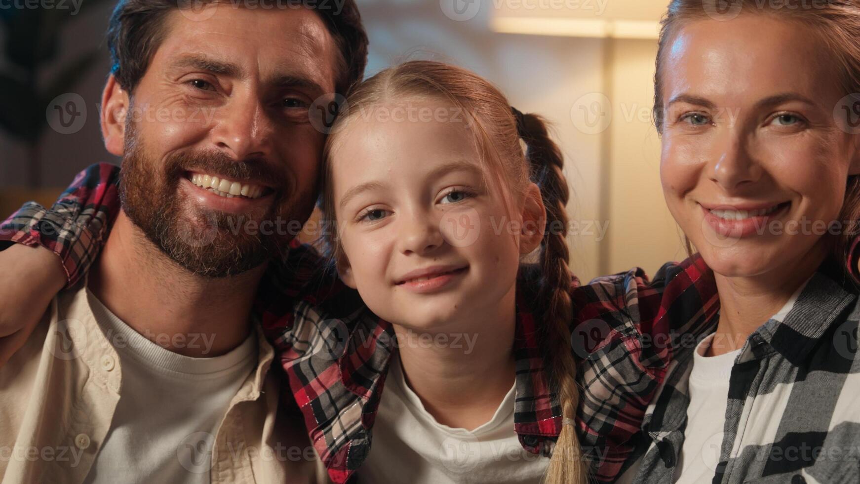 Happy Caucasian family portrait at home evening carefree parents mother woman man father kissing in cheeks little daughter child kid girl love adopt custody childcare bonding looking smiling at camera photo
