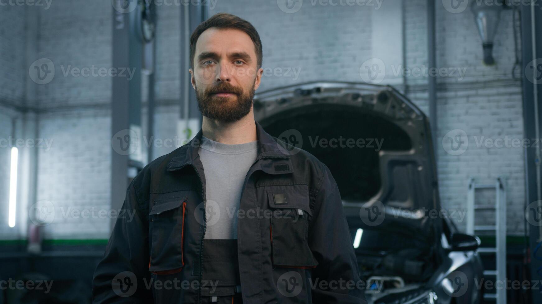 Portrait of smiling auto mechanic technical employee in work uniform looking camera at car repair service station happy male specialist Caucasian bearded man smiling concept of automobile maintenance photo