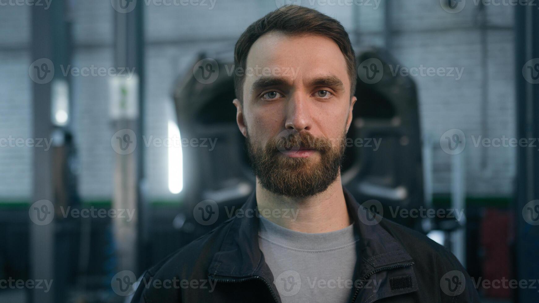Close up portrait adult guy Caucasian man male industrial worker auto mechanic technician professional engineer repairman in uniform serious face looking camera in car service garage machinery factory photo