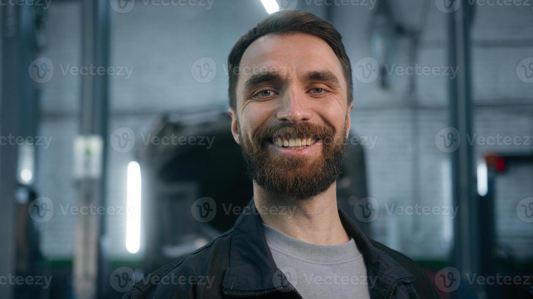 Happy man Caucasian bearded smiling male professional mechanic service manager auto engineer car serviceman technical worker posing in repair vehicle station garage looking at camera positive smile photo