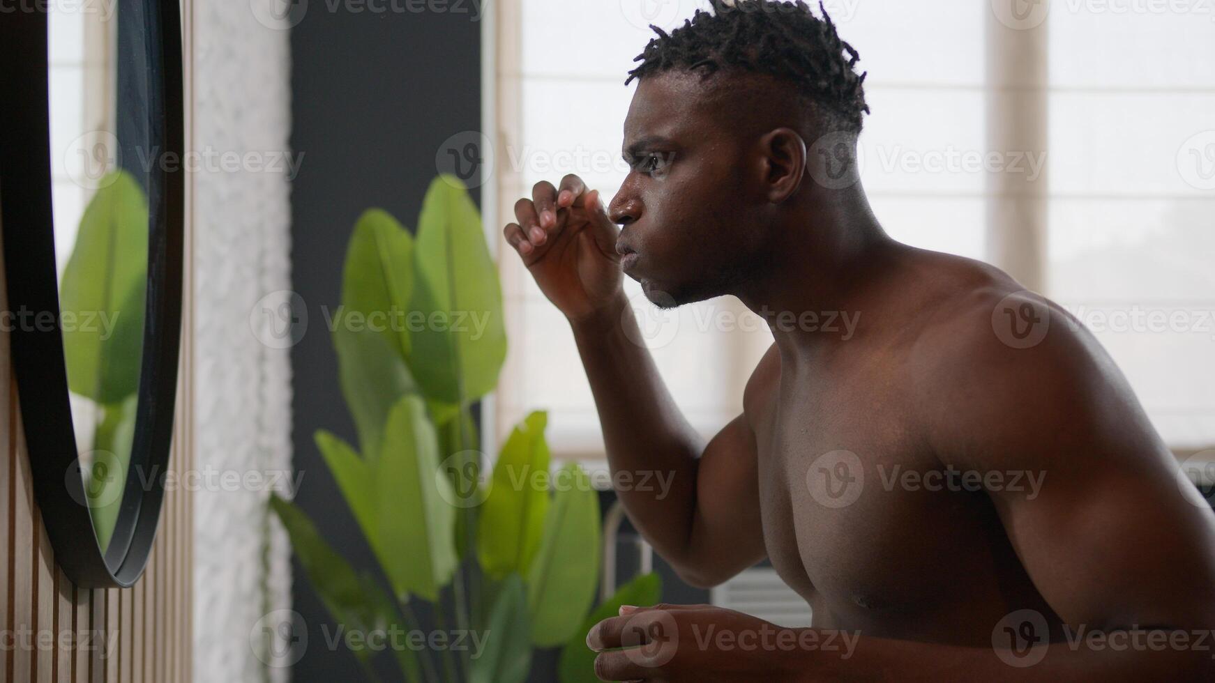 African American man looking in mirror touch coarse hair dreadlocks upset anxious guy suffer baldness alopecia problem skincare treatment with hairstyle repair cosmetic product male beauty in bathroom photo