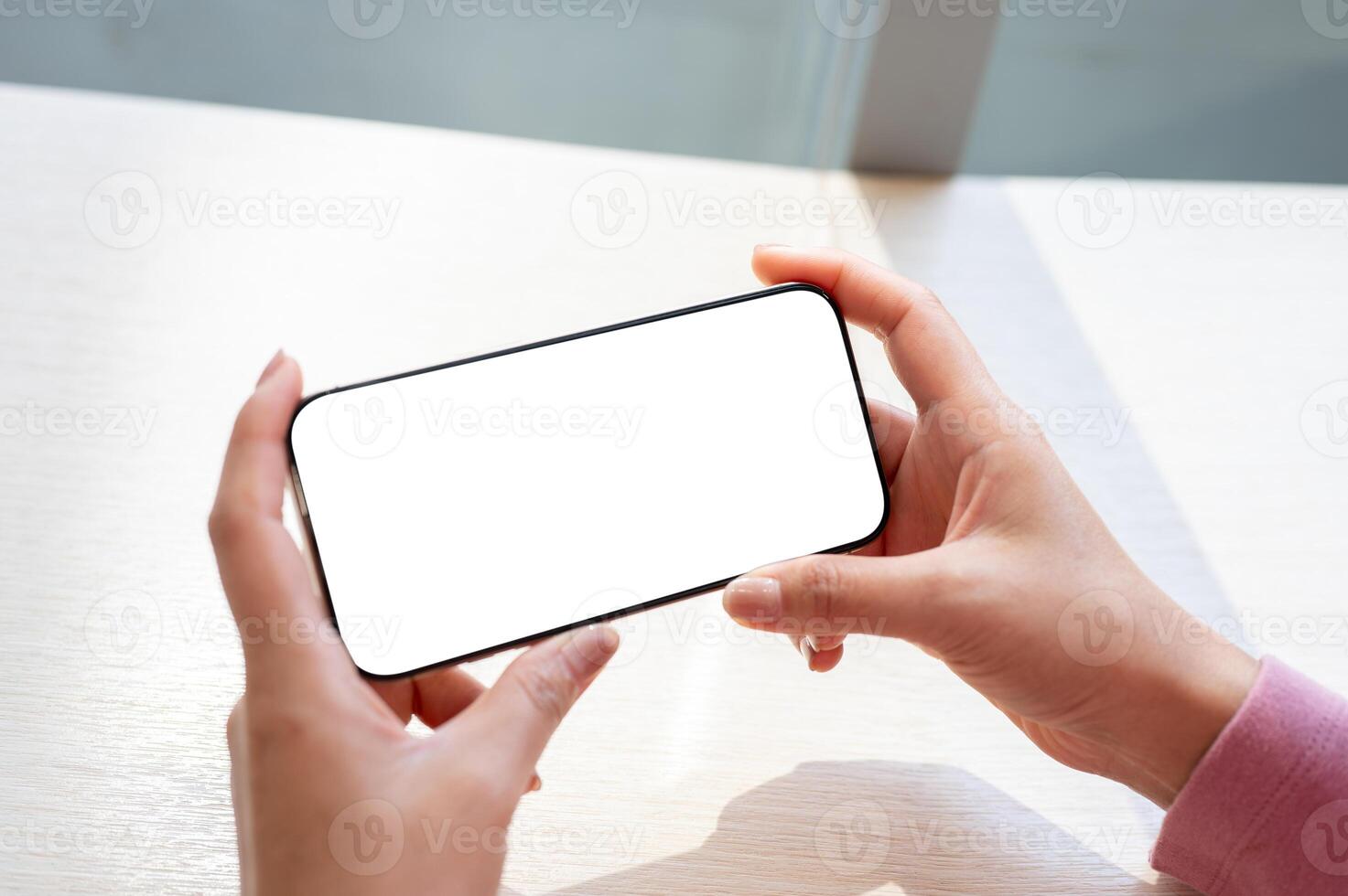 A close-up top view of a woman's hand holding a smartphone horizontally. photo