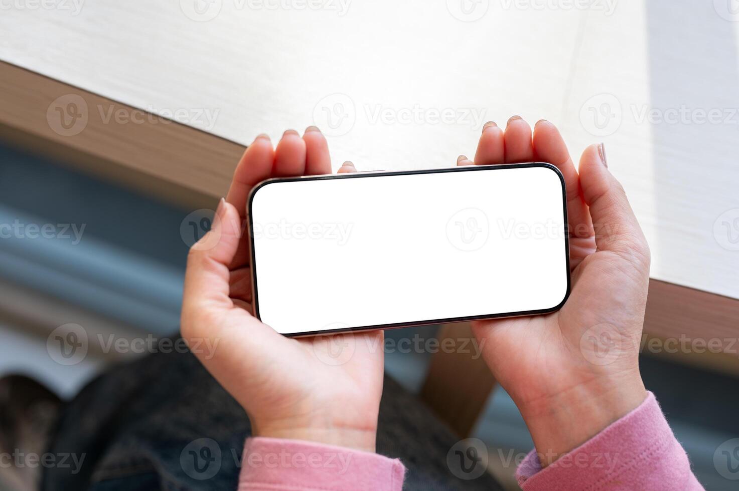 A close-up top view of a woman's hand holding a smartphone horizontally while watching a . photo
