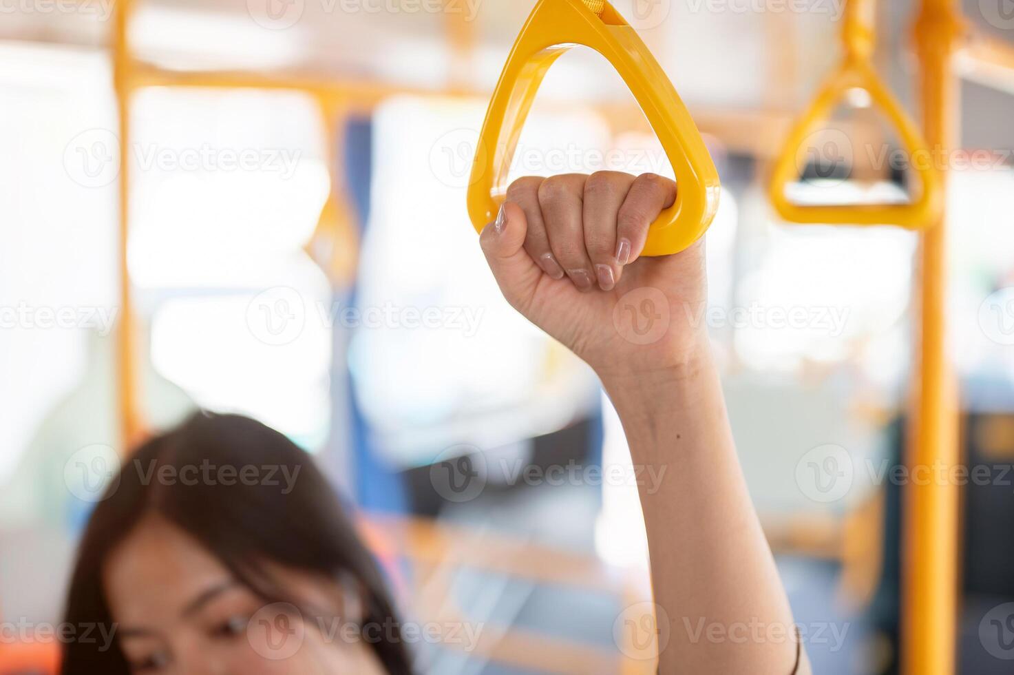 A close-up of a woman holding a handrail while commuting on a public bus in the city. photo