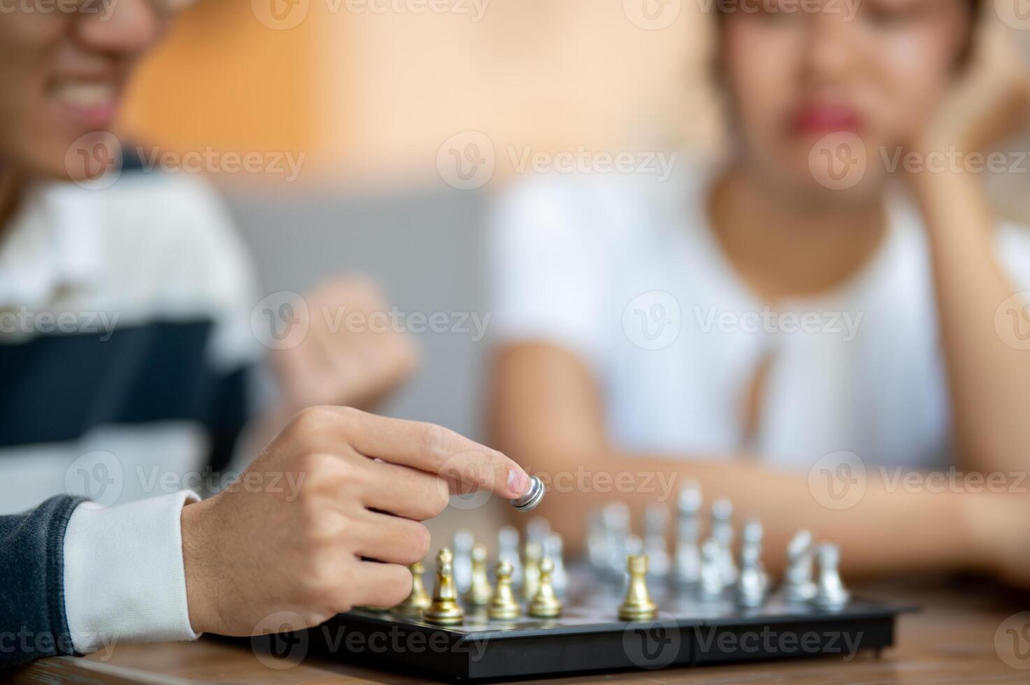 A close-up of a man playing chess with his friend, moving a piece on the board. photo
