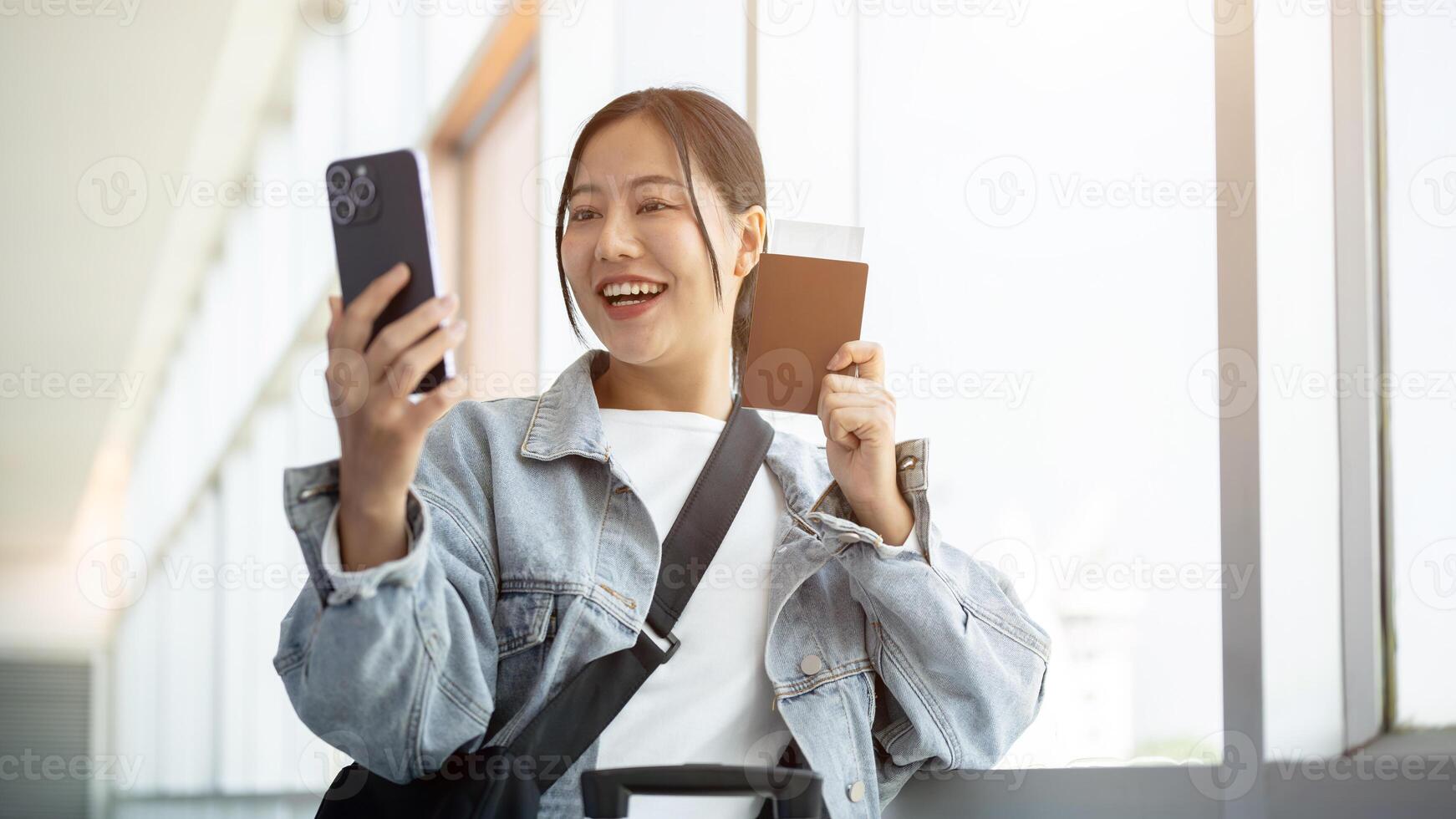 An excited Asian female passenger enjoys talking on a call while waiting for her flight. photo