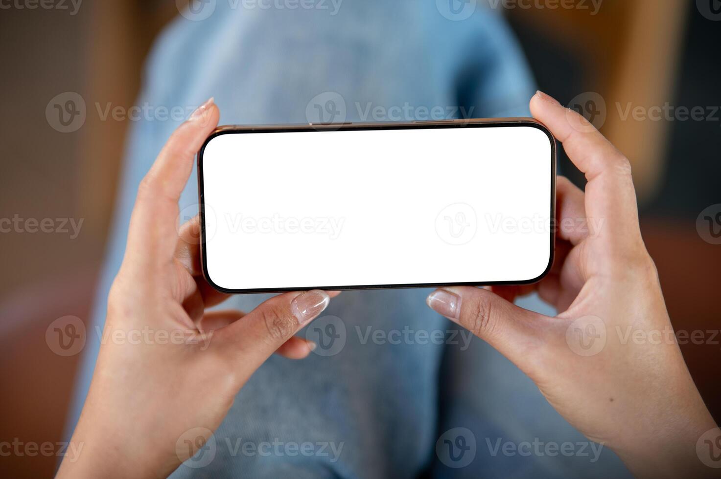 A close-up top view of a woman using a smartphone while sitting indoors, watching a . photo