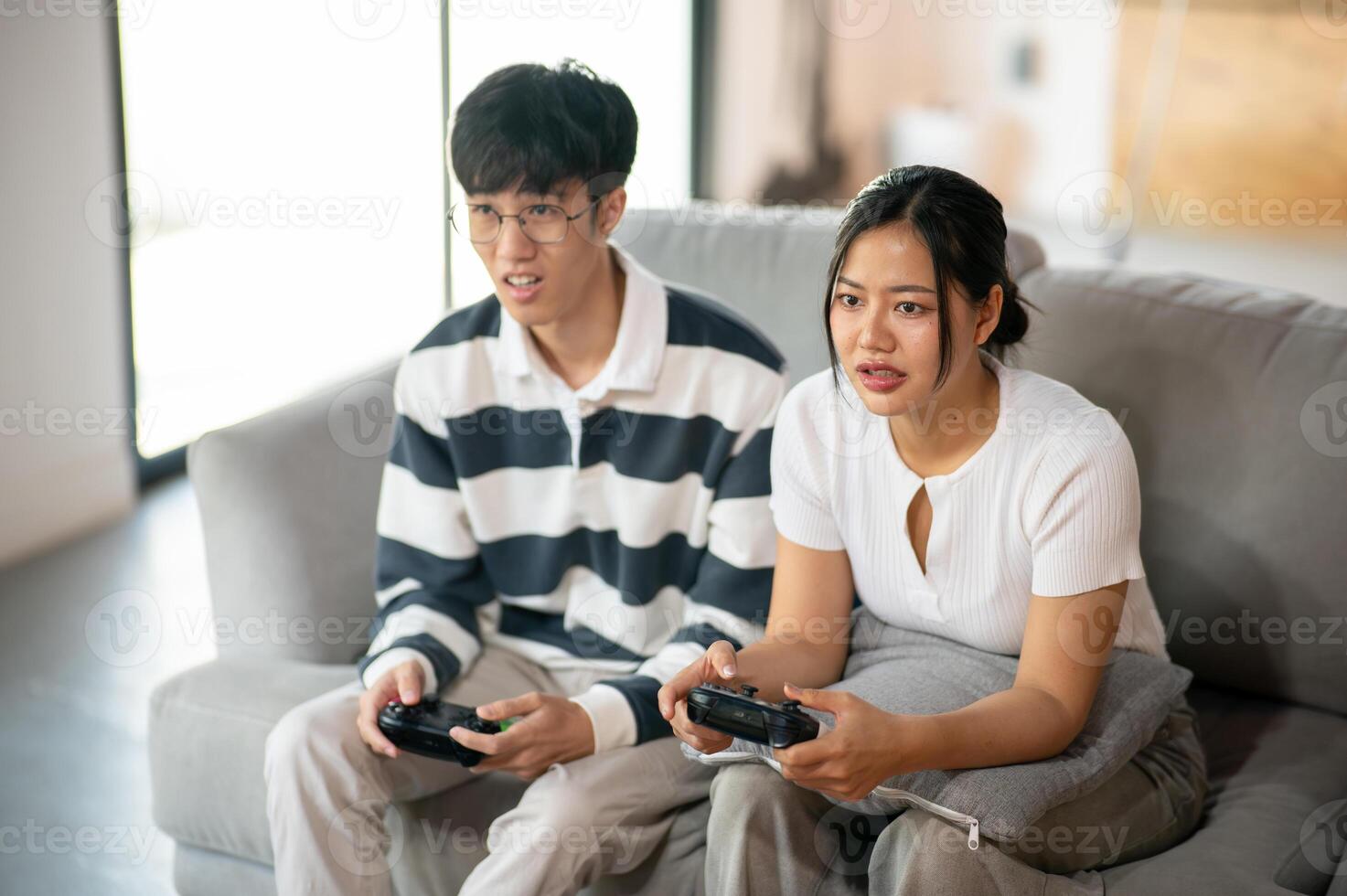Two young Asian friends, a male and a female, are playing a game together at home. photo