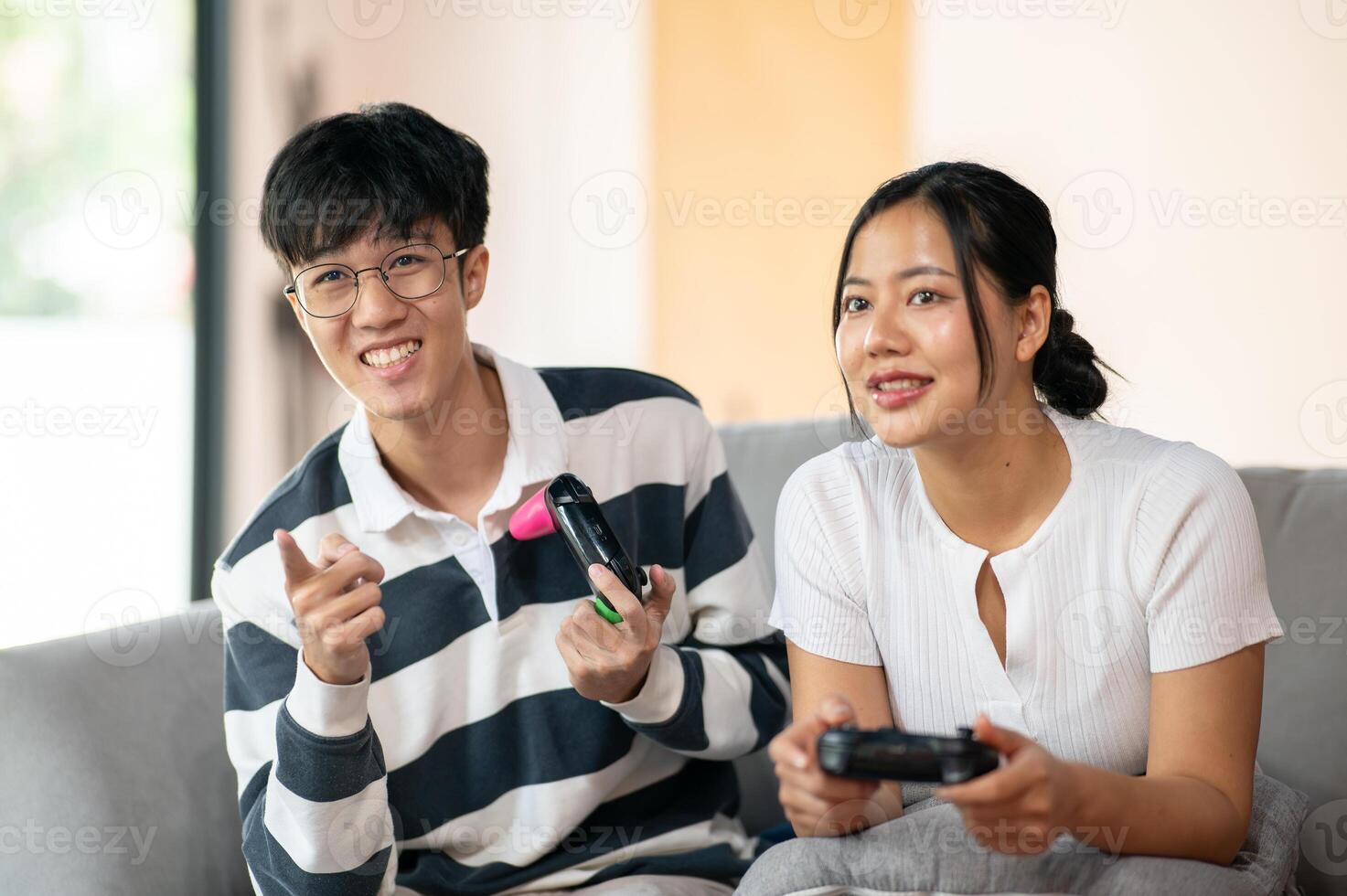 Two cheerful Asian friends are enjoy playing a game on the sofa in the living room together. photo