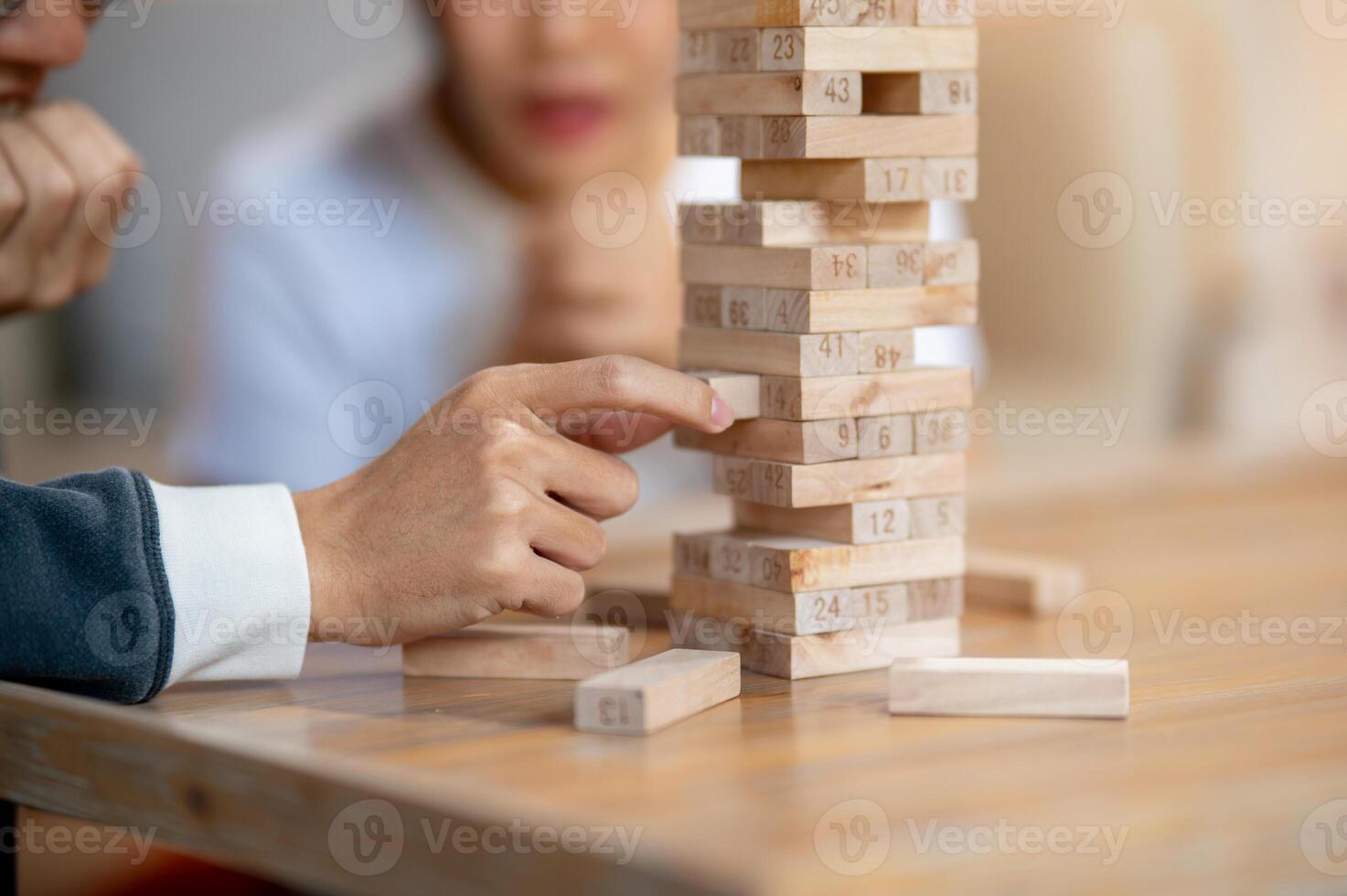 A close-up of a man's fingers carefully removing a wooden block while playing Jenga at home. photo