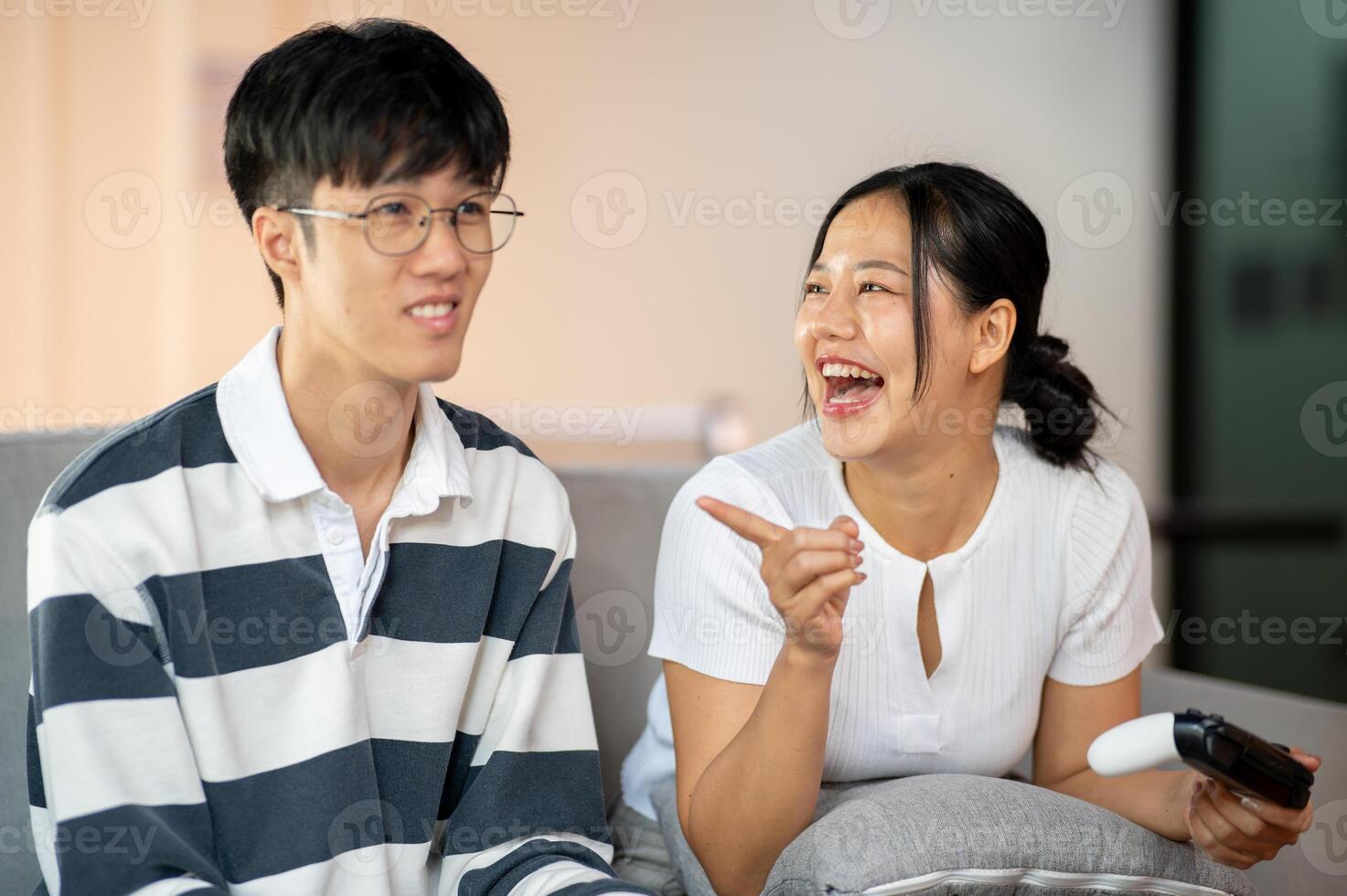 Two cheerful and joyful Asian friends are enjoy playing a game on the sofa together. photo
