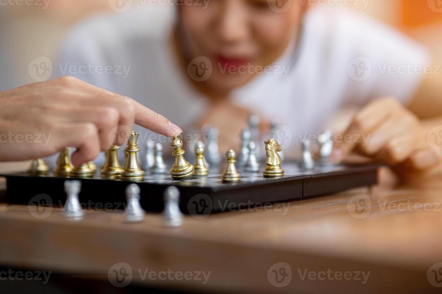 A man playing chess with his friend, moving a piece on the board. photo