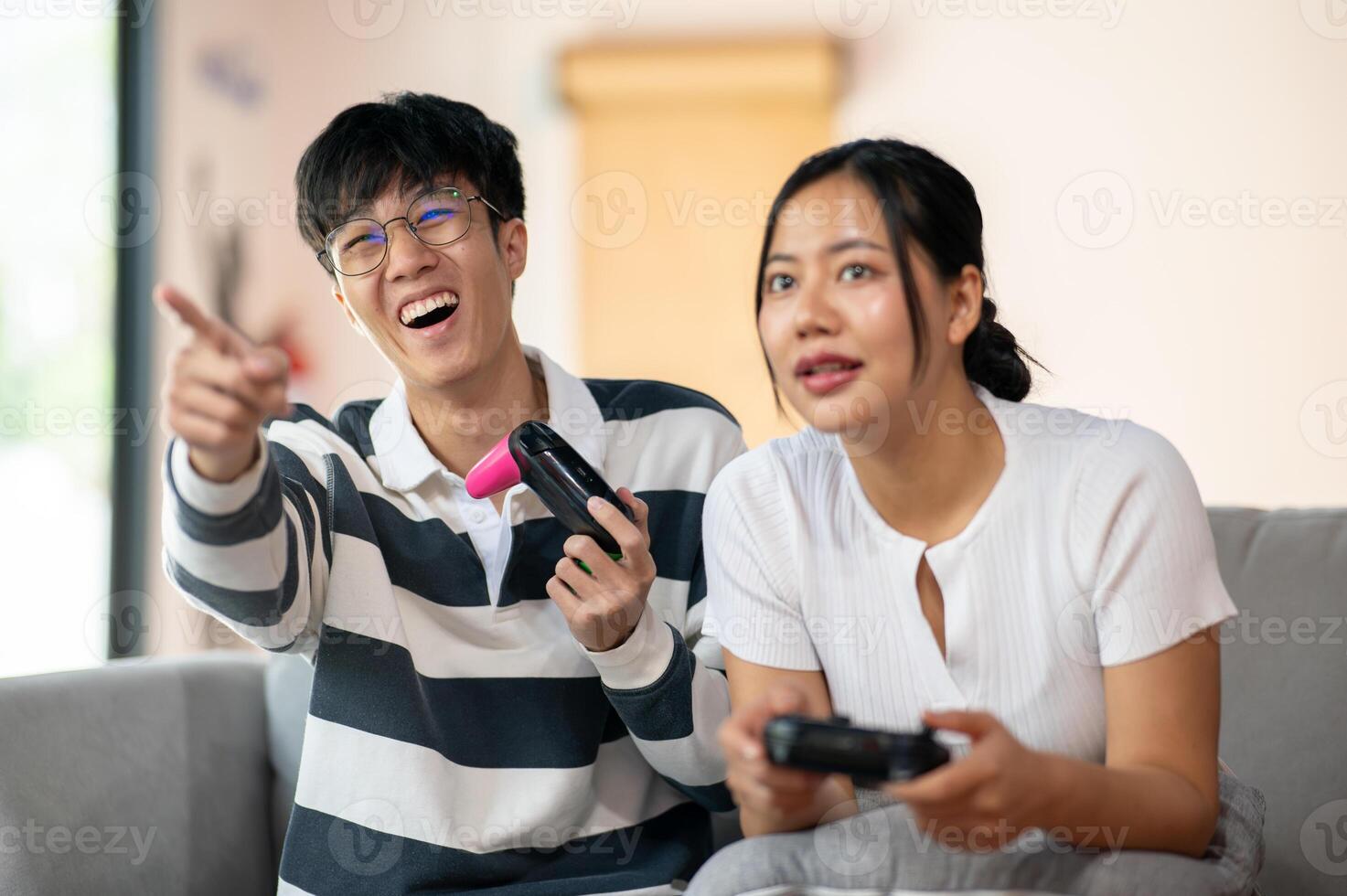 Two cheerful and joyful Asian friends are enjoy playing a game in the living room together. photo