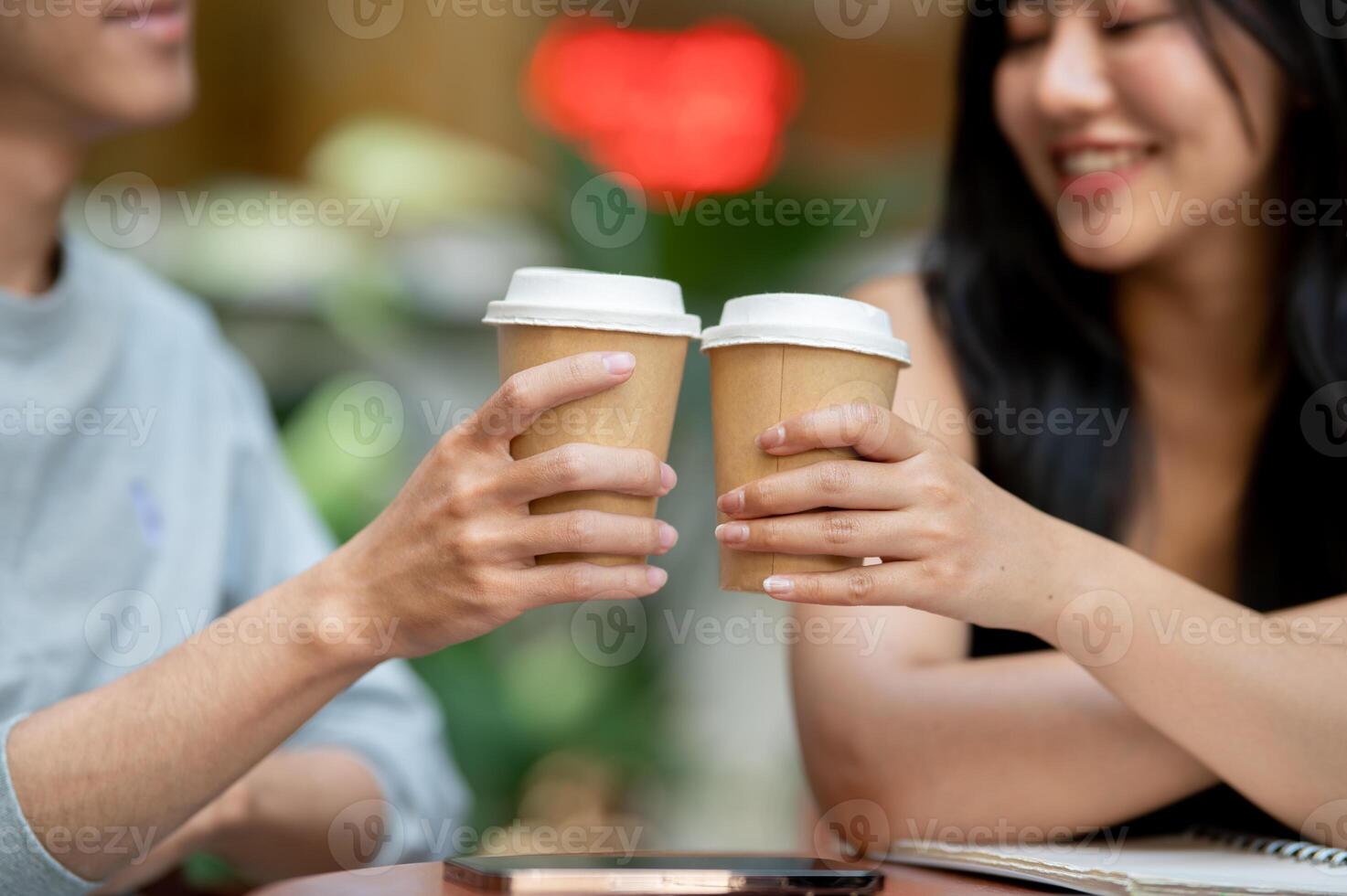 A close-up of a positive, smiling Asian couple or friends enjoying coffee together at a coffee shop. photo