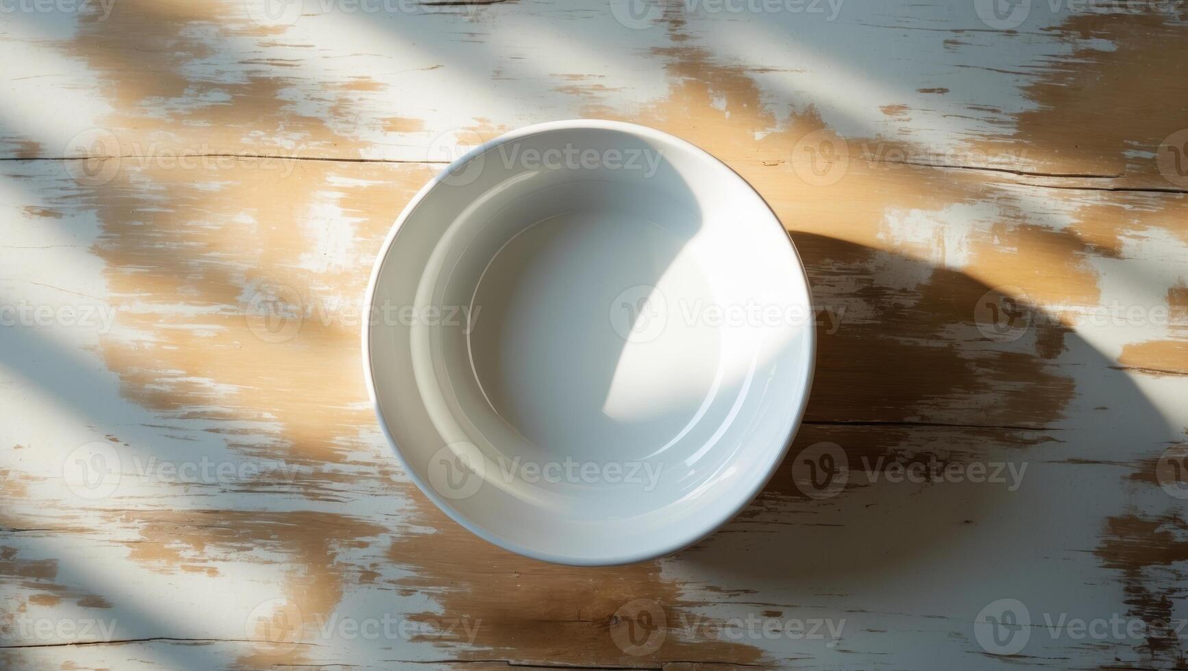 A plain white ceramic bowl, placed on a rustic wooden table with subtle natural lighting. photo