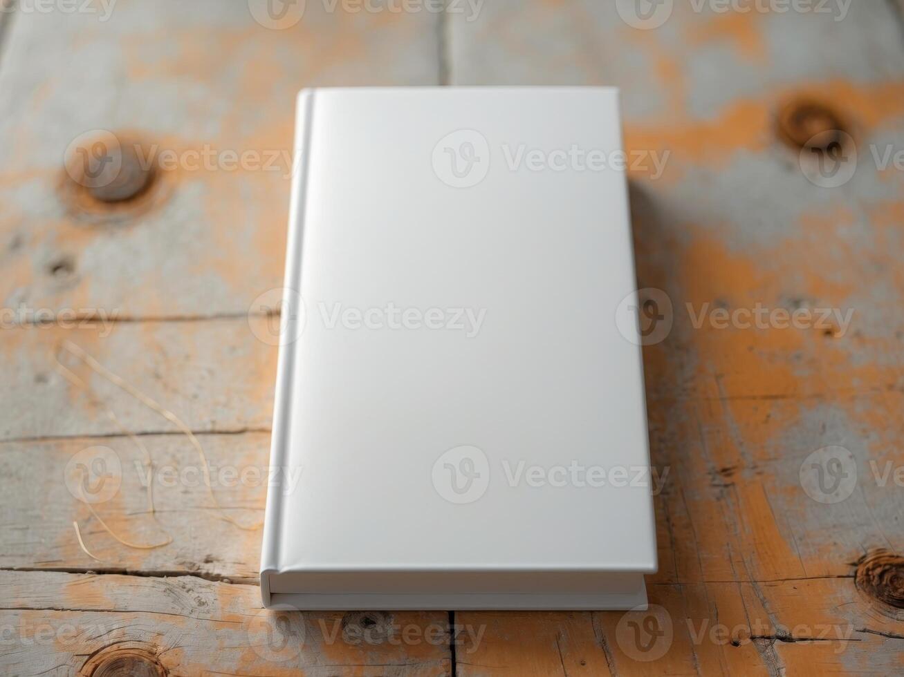 White book with a blank cover standing upright on a rustic wooden surface photo