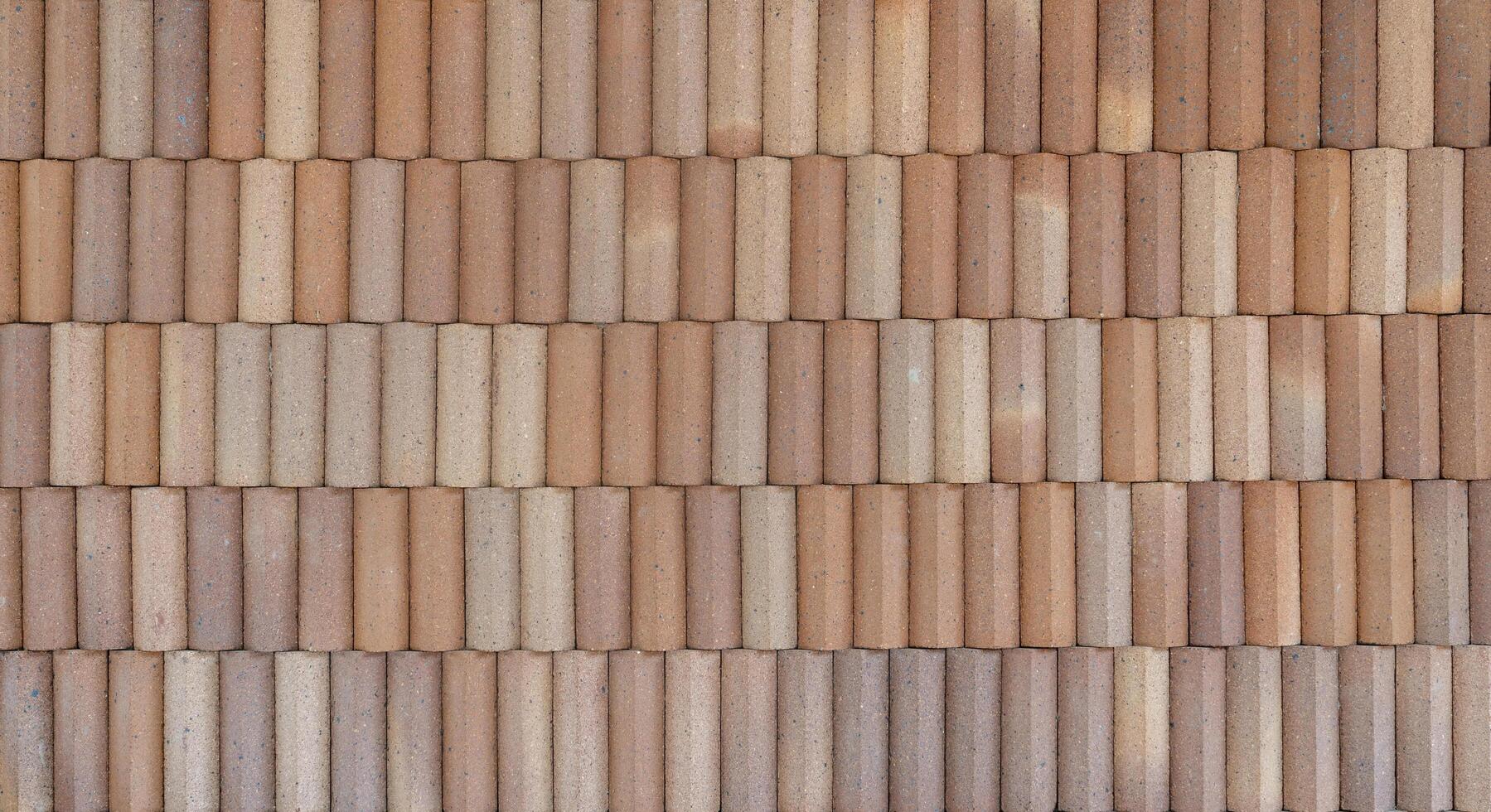 A textured brick wall with cylindrical clay bricks arranged in a horizontal pattern, creating a rustic and earthy surface. photo