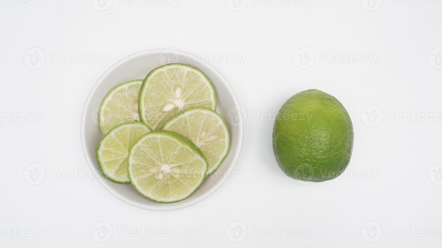 Slices Fresh Green Lime Fruit on Bowl on White Background photo