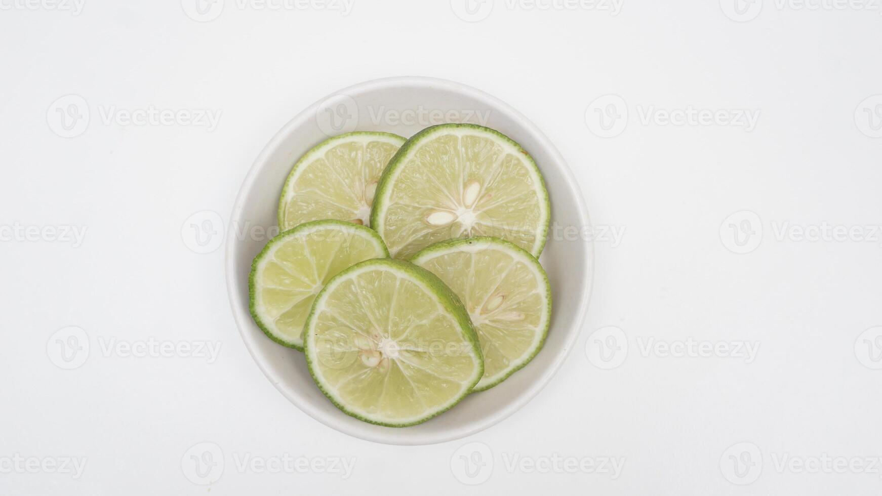 Slices Fresh Green Lime on Bowl on White Background photo