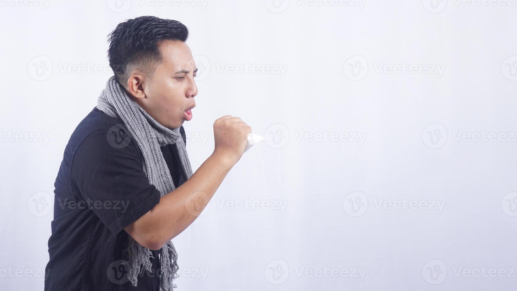 Young Asian Man with Scarf Suffering from Cough on White Background photo