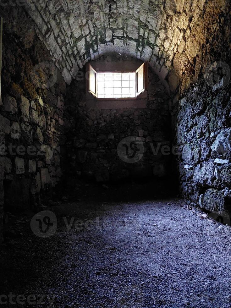 Medieval dungeon with stone walls and a small hatch photo