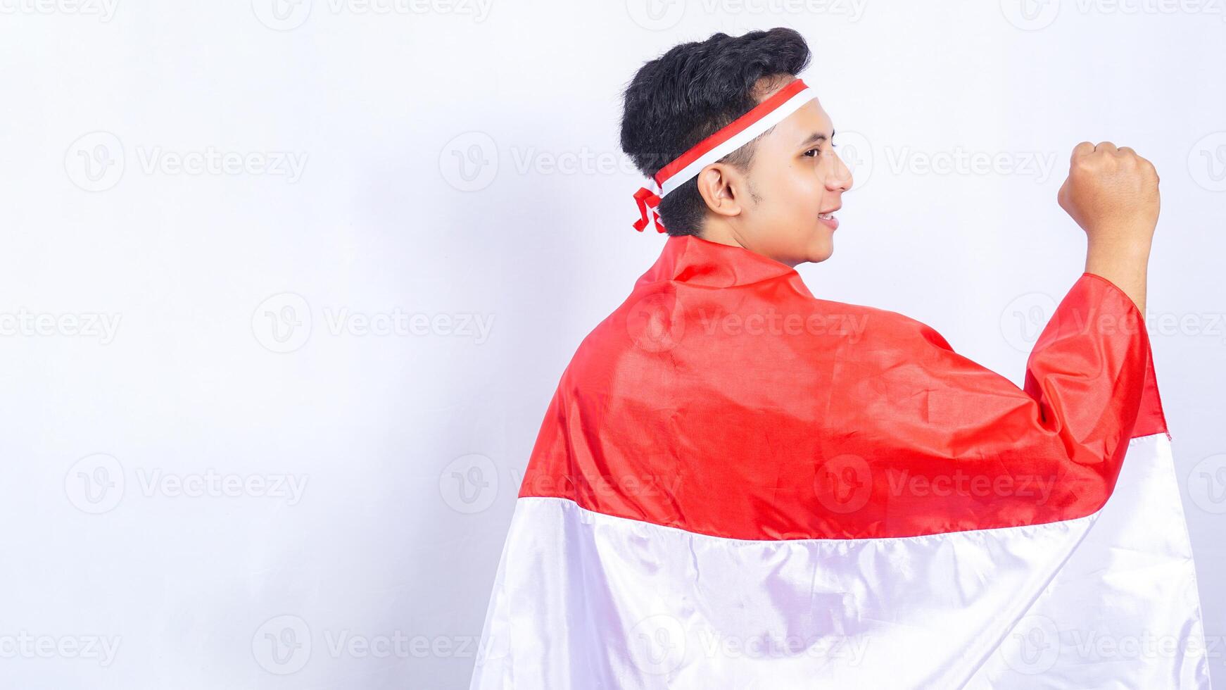 Rear View of Man Holding Red and White Indonesia Flag Behind Back on White Background photo