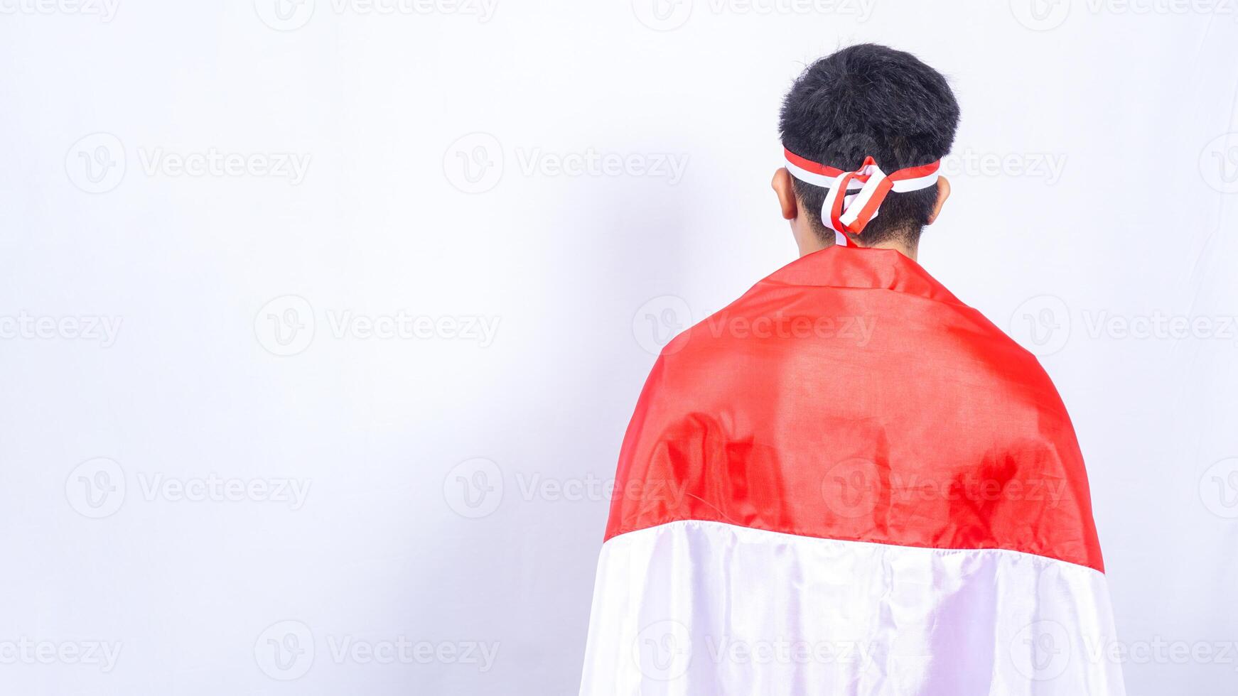 Smiling Indonesian Man Holding Red and White Indonesia Flag Behind Back on White Background photo