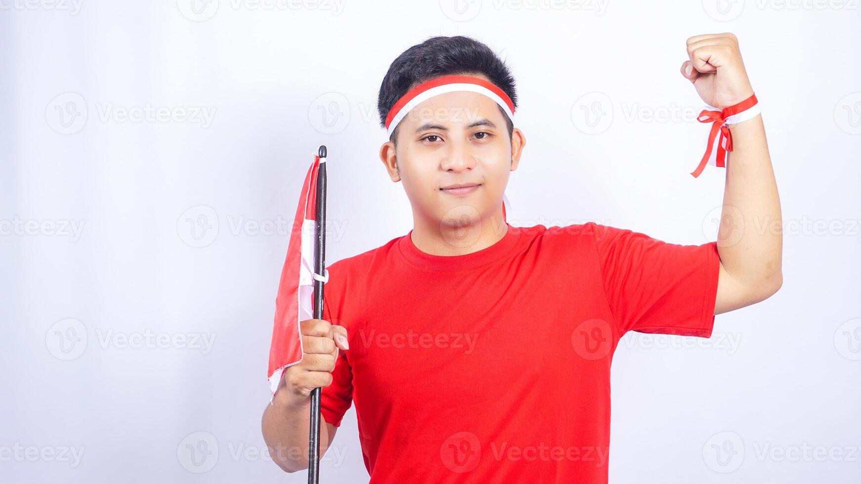 Indonesian Man Smiling while Holding Red and White Indonesia Flag on White Background photo