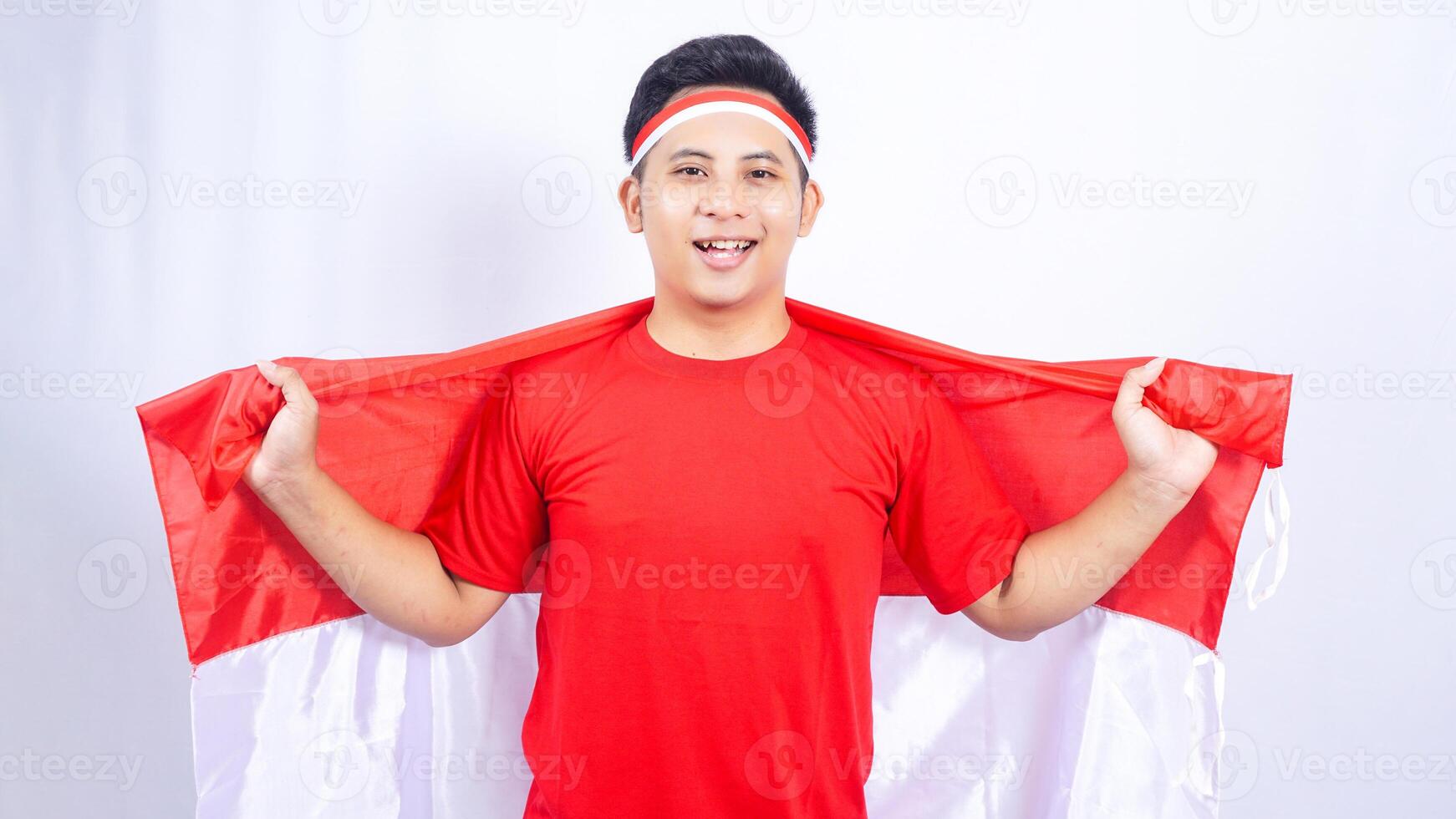Indonesian Man Holding Red and White Indonesia Flag Behind Back on White Background photo