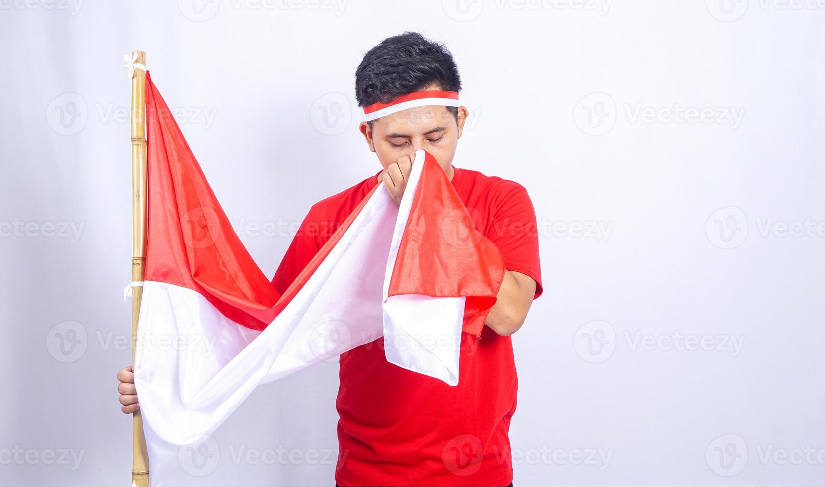 Portrait of Indonesian Man Kiss The Country Flag on White Background photo