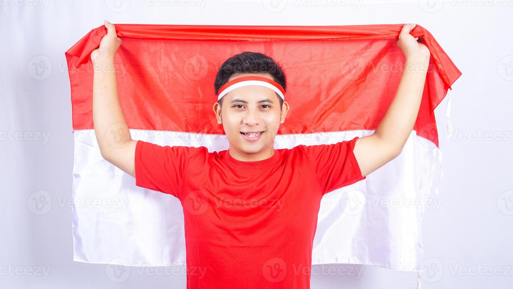 Indonesian Man Covering Bottom Part of His Face with Red and White Indonesia Flag on White Background photo