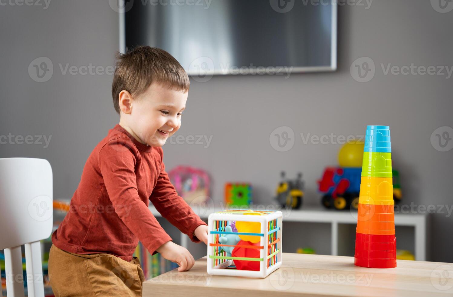 A cute little toddler boy of two years old plays with multi-colored balls and sits at a children's table in his room. Tactile sensory balls. Educational toys for children photo