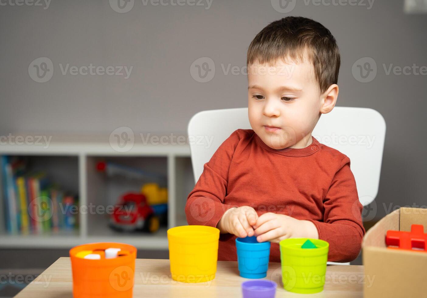 A beautiful little boy of two or three years old sits at a table photo