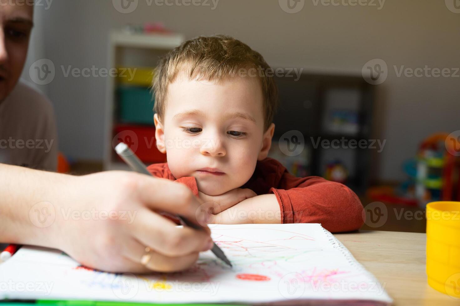 A cute little toddler boy of two years old with dad draws with markers photo