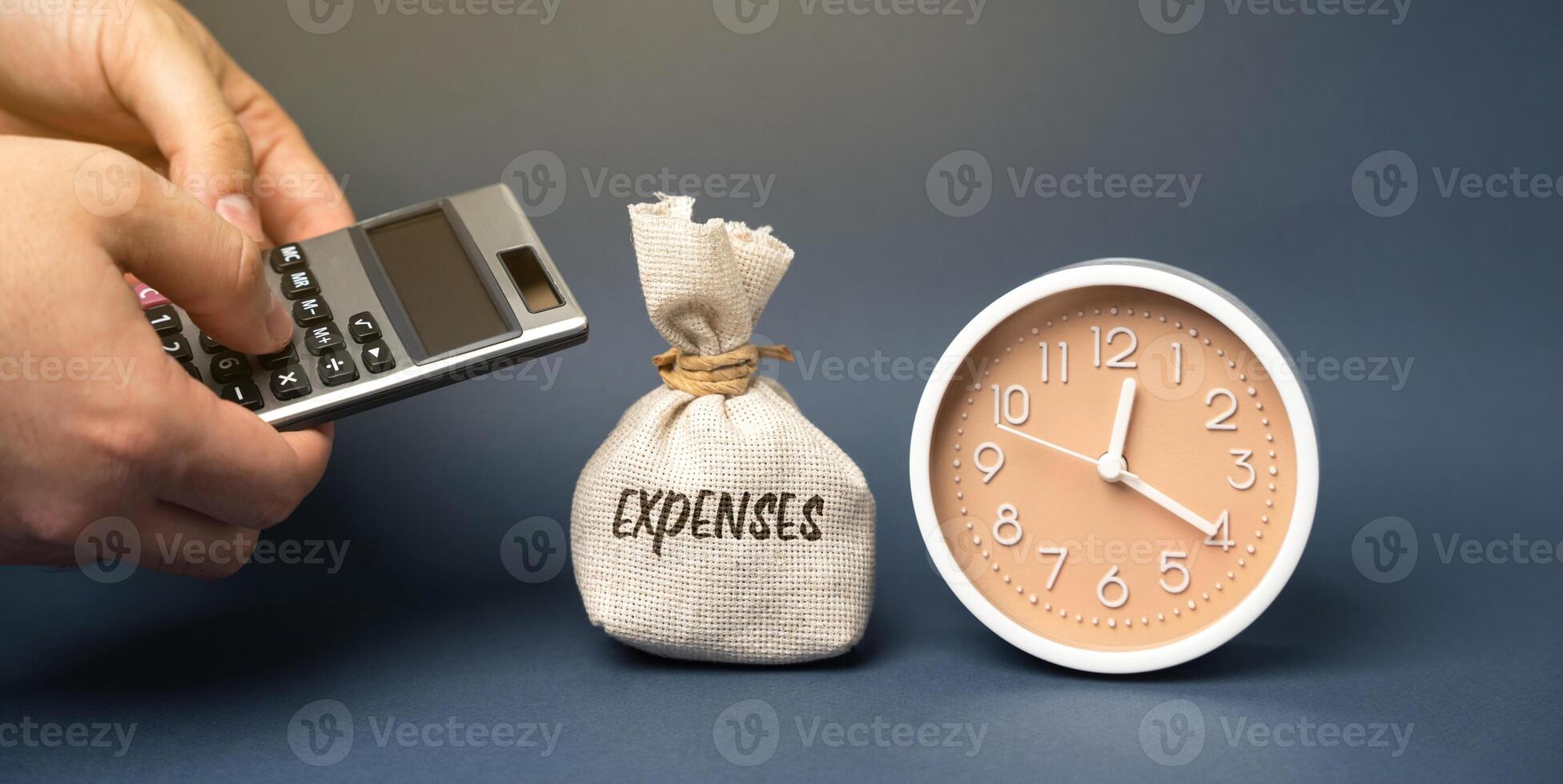 Money bag with the word Expenses. Outflow of money as payment for goods or service. The amount of the taxpayer's expenses in cash. Business concept. Man with a calculator in his hands and clock photo