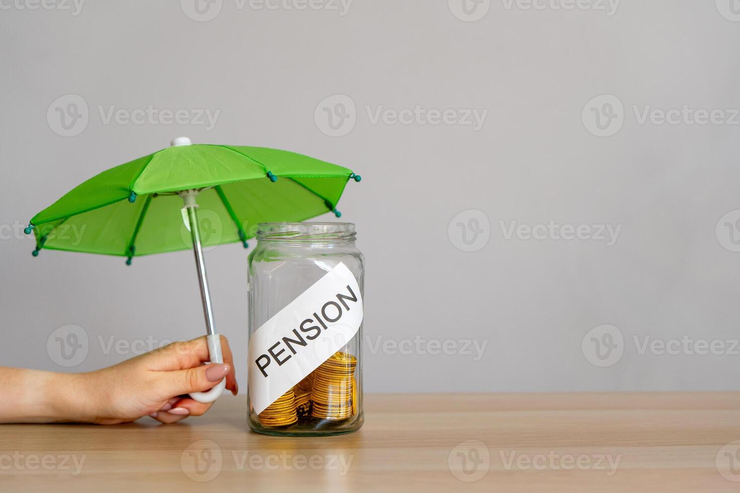 Bank of coins with the inscription Pension and green umbrella. Retirement Insurance concept. Financial support and regular payments to people after retirement. Business and finance photo