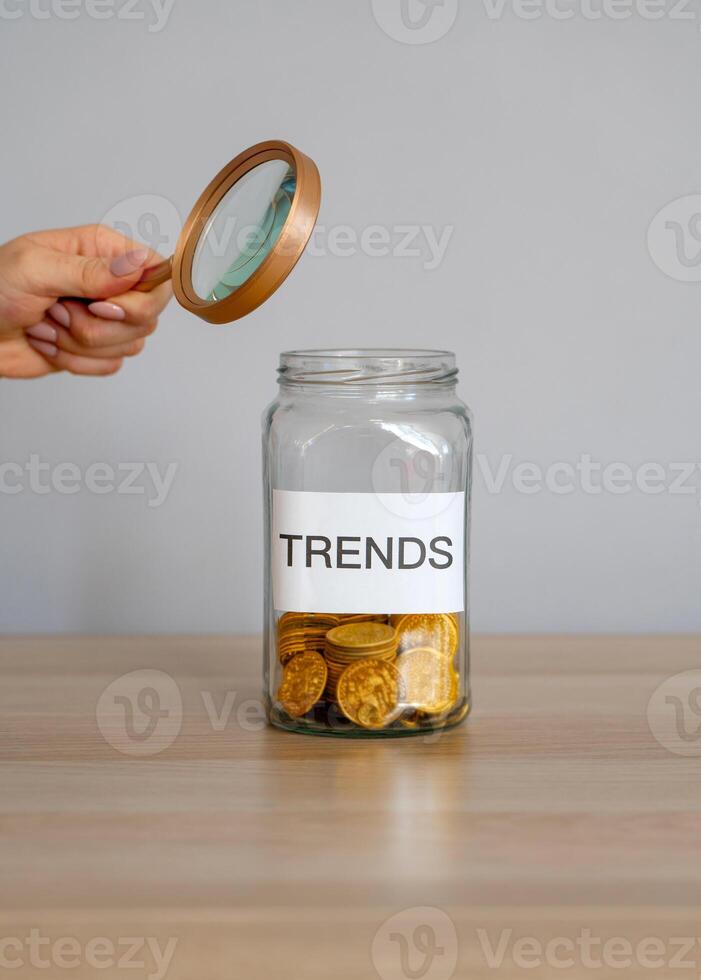 Bank of coins with the inscription Trends and magnifying glass. Analysis popular and relevant topics. New ideological trends of fashion. Recent and latest trend. Business and finance. Investments photo