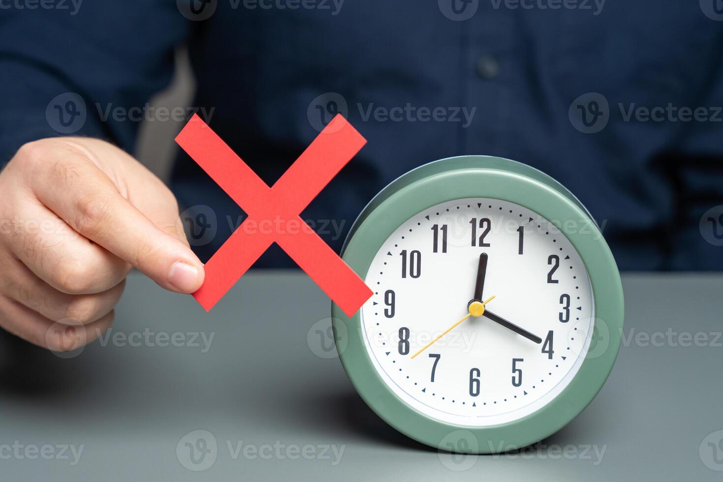 A man is holding a red no prohibition sign near clock. Prohibition of time change. Summer and winter time. Review laws, regulations photo