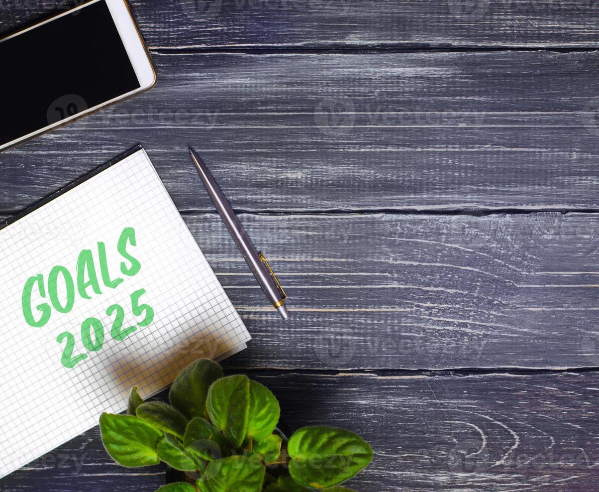 Notes with words Goals 2025 and pen with phone. Motivation, inspiration. Planning, plans and tasks. New business ideas. Setting goal photo