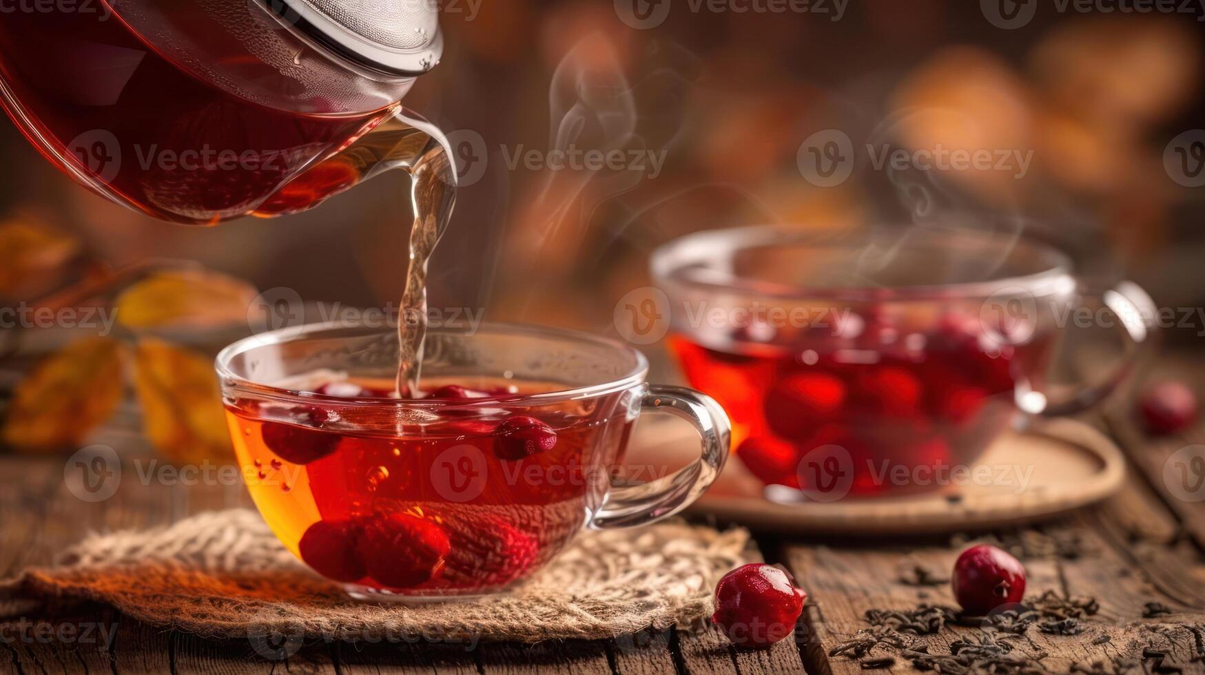 Warm tea being poured into a glass cup with raspberries, autumn leaves in the background photo