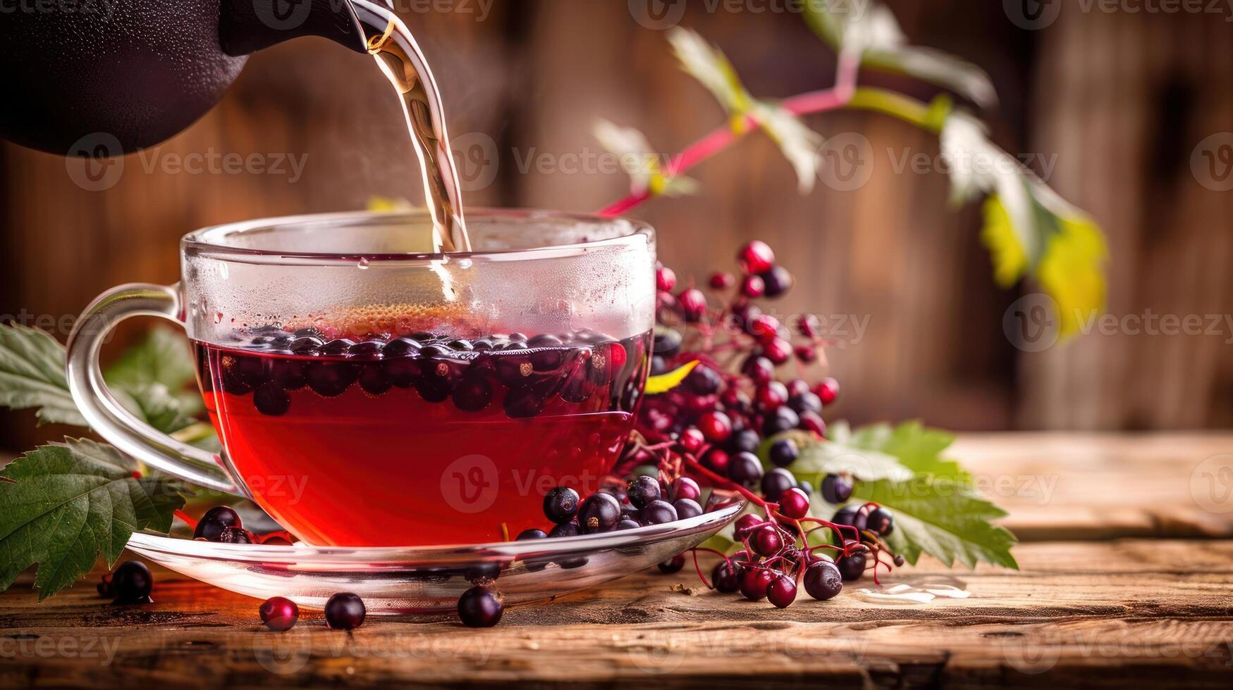 Pouring herbal tea into a glass cup with berries and leaves on a rustic wooden table photo